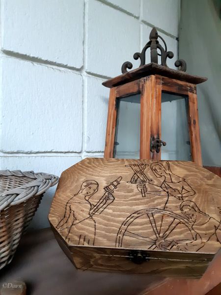 Wood burned box with a medieval woodcut image of three women in the process of producing yarn on the lid.