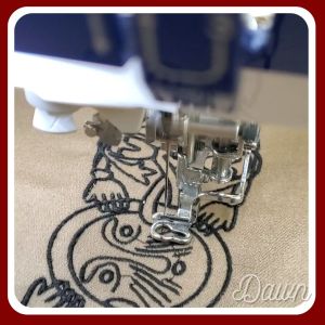 Stitching the Mammen large face and hands design onto tan wool